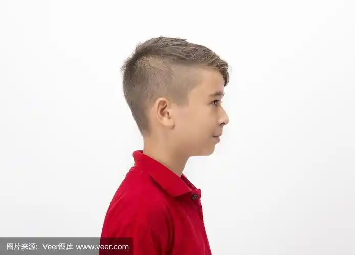 小男孩的侧面视图,站在白色的背景看走开与空白的面部表情