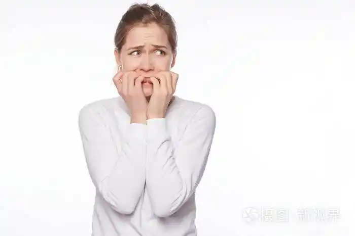 一幅可怕的可爱的不安全的女人的肖像金发和灰色的眼睛咬着指甲恐惧地