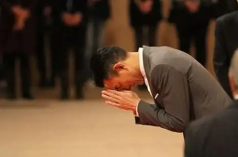 刘德华身着灰西装现身双手合十行礼图