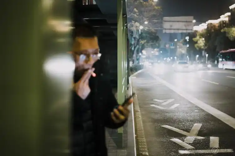 夜色里的公交车站,抽烟等待公交的男子.