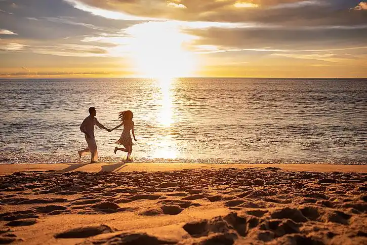 快乐的年轻夫妇在沙滩奔跑