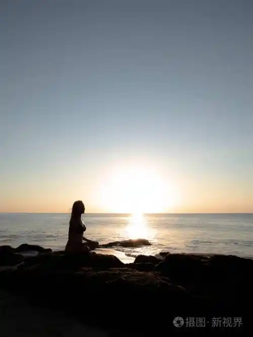 女人坐在岩石上练习瑜伽欣赏海景巴厘岛海滩上的瑜伽