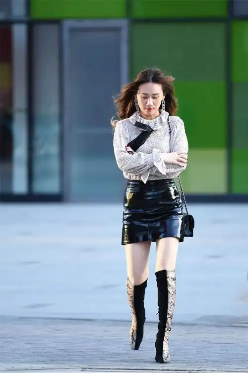 街拍美女高腰的黑色漆皮短裙搭配拼接色的过膝靴非常洋气