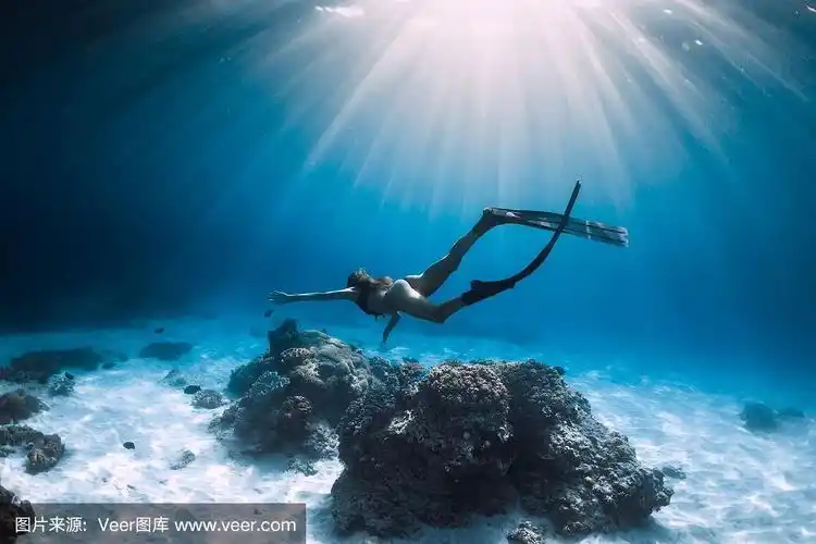 女自由潜水者用鳍在沙海上滑翔.在蓝色的海洋里自由潜水