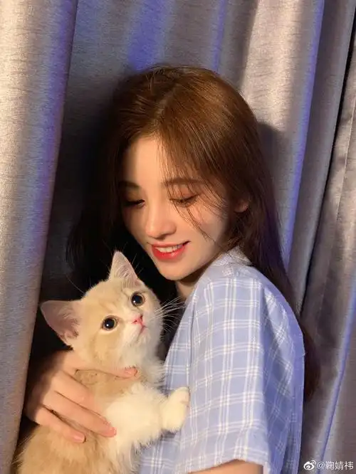 照片中,鞠婧祎身穿淡蓝色格纹上衣,怀中抱着可爱的小猫,她还忍不住亲