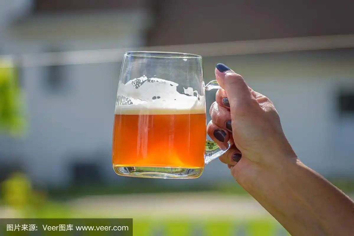 夏日阳光下女人的手捧着啤酒杯