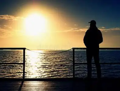 朝阳大海码头板上的成年高个子男人看着大海到朝阳. 光滑的水位照片