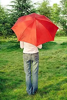 户外伞下的年轻女人背影