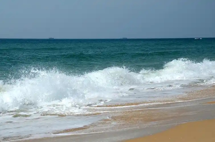 海水涨潮了,海水中的波浪一个连着一个向岸边涌来,溅起雪白的浪花,令