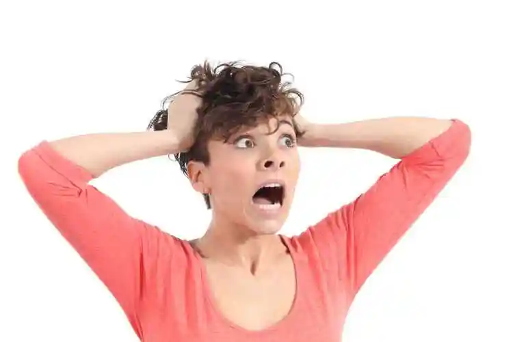 白色背景下穿粉衣服的女人抓着自己的头发尖叫