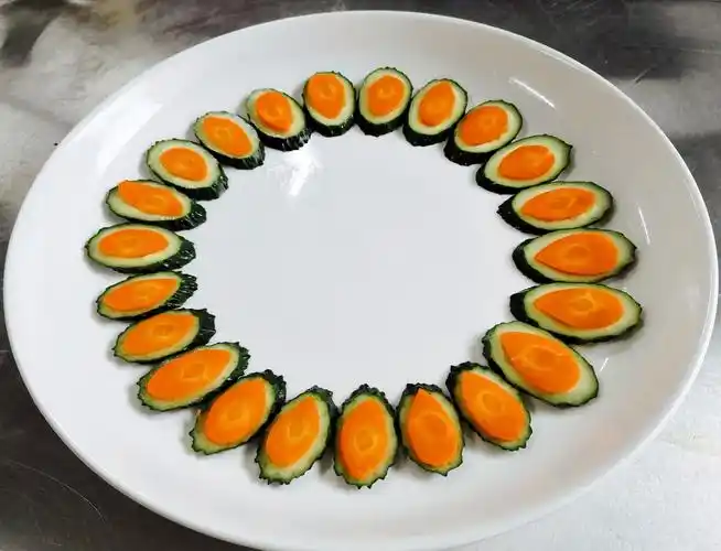 接下来,用青黄瓜洗净切斜刀厚片,搭配胡萝卜斜刀片削成的叶形,组合摆