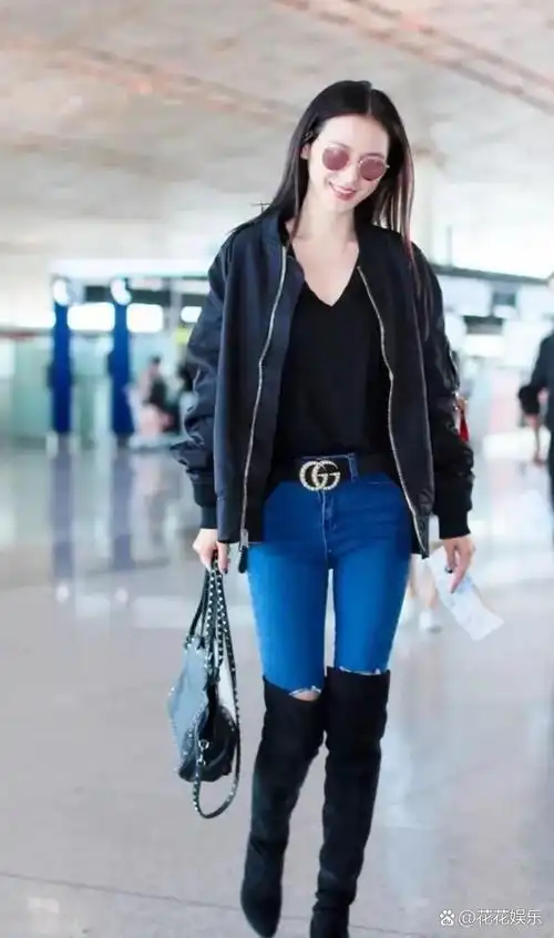张予曦机场秀穿搭,黑色棒球服外套搭配破洞牛仔裤长靴子,妥妥的女明星