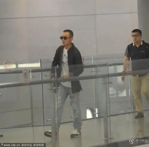 组图:文章低调现身机场 独自一人抽烟解闷