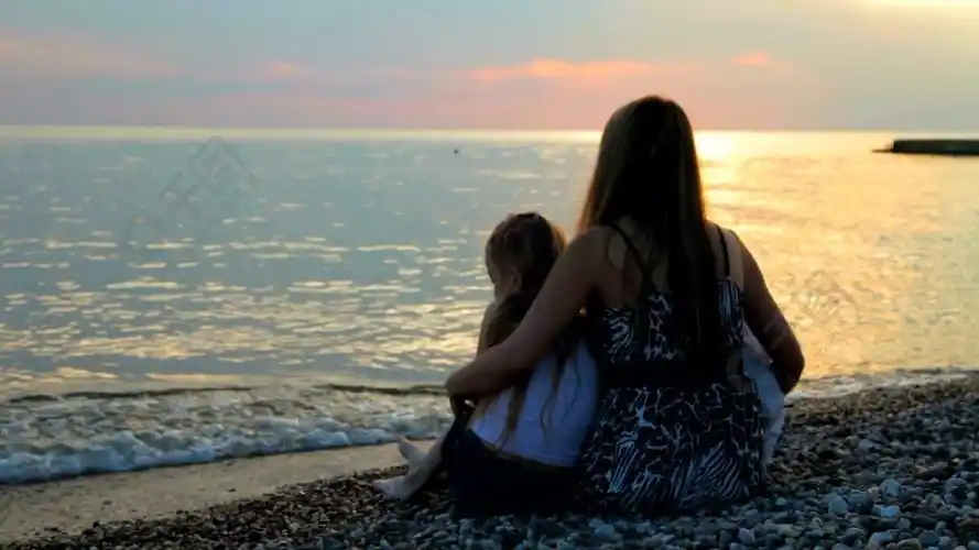 母亲带着两个女儿在日落海滩