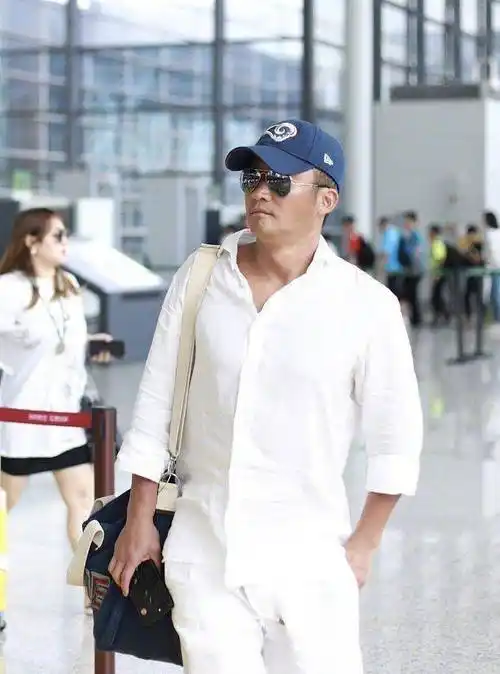 原创45岁吴京现身机场,白衣配"马蹄鞋"混搭出时髦感,美黑肤色抢镜