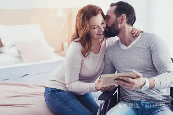 坐在轮椅上的大胡子男子亲吻他的妻子