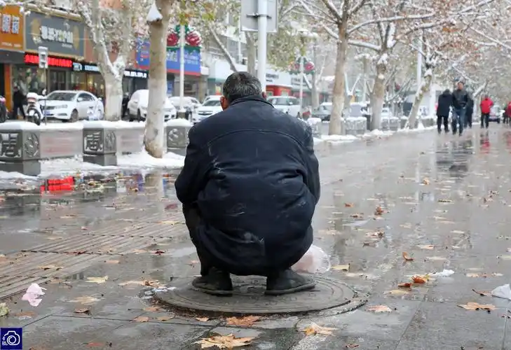 洛阳的最低气温达到了零下10度,西工区周王城广场附近,两名男子轮流蹲