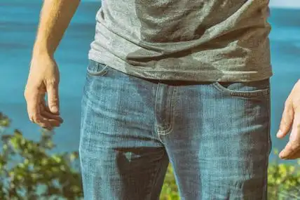 一个穿着湿牛仔裤的男人站在海滩上照片