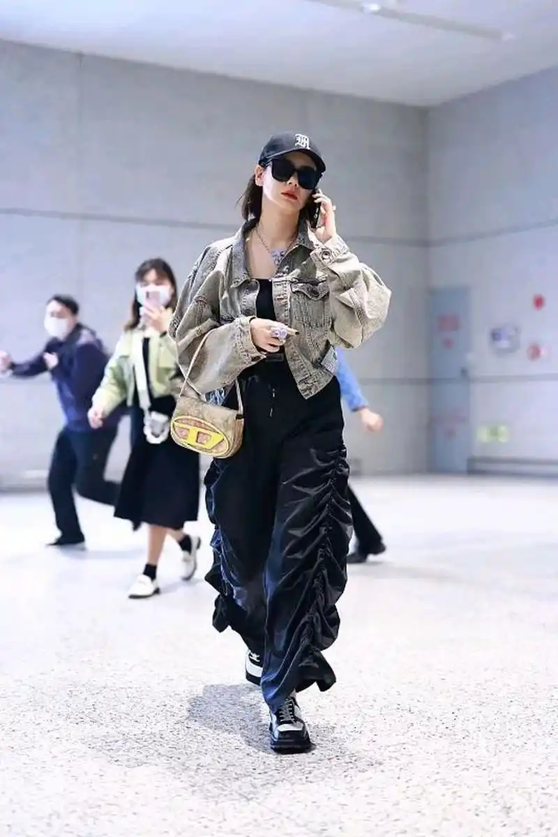 戚薇街拍,她穿了一件灰色的短款牛仔外套,内搭一件黑色小背心,搭配一