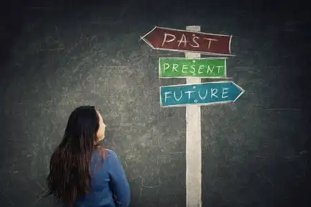 后视镜女人在黑板前看着一个路标,箭头显示过去的现在和未来.