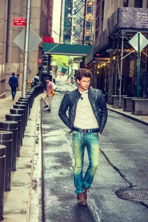 一个打扮时尚的男人在雨后在狭窄潮湿的街道上行走