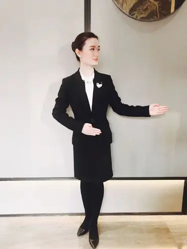 标准站姿,面带微笑,手臂略低于肩膀,五指并拢,大拇指内扣,眼神看向