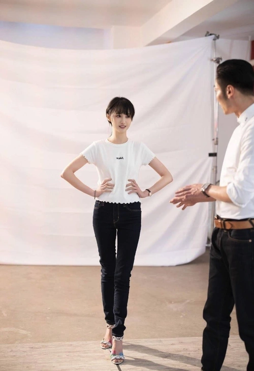 郑爽穿着深蓝色牛仔裤,浅蓝色上衣,可能天气有些冷,她双手交叉裹住