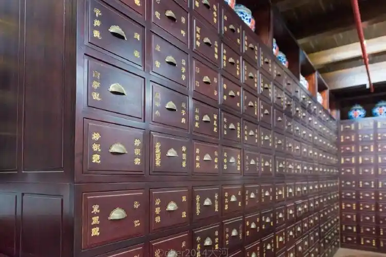 工作人员正在忙着给各种中药材分类称重,一个个药柜整齐排列,这里隐藏