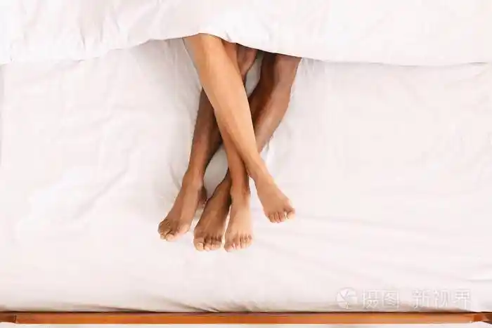 男女双腿躺在被子下躺在床上