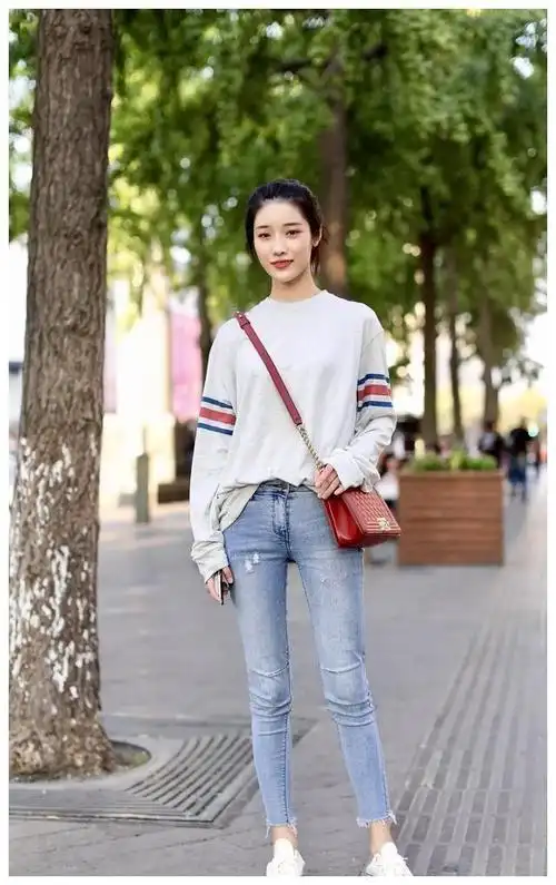 路人的街拍,美女们穿着浅蓝色牛仔裤和休闲上衣,凸显出一个妩媚时尚的