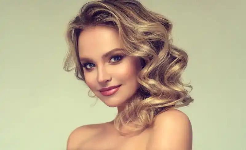 脸上带着温柔微笑的美女正在展示卷曲的长发.女孩,优雅.