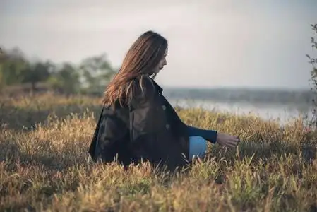 悲伤的女人独自坐在空旷的田野里照片