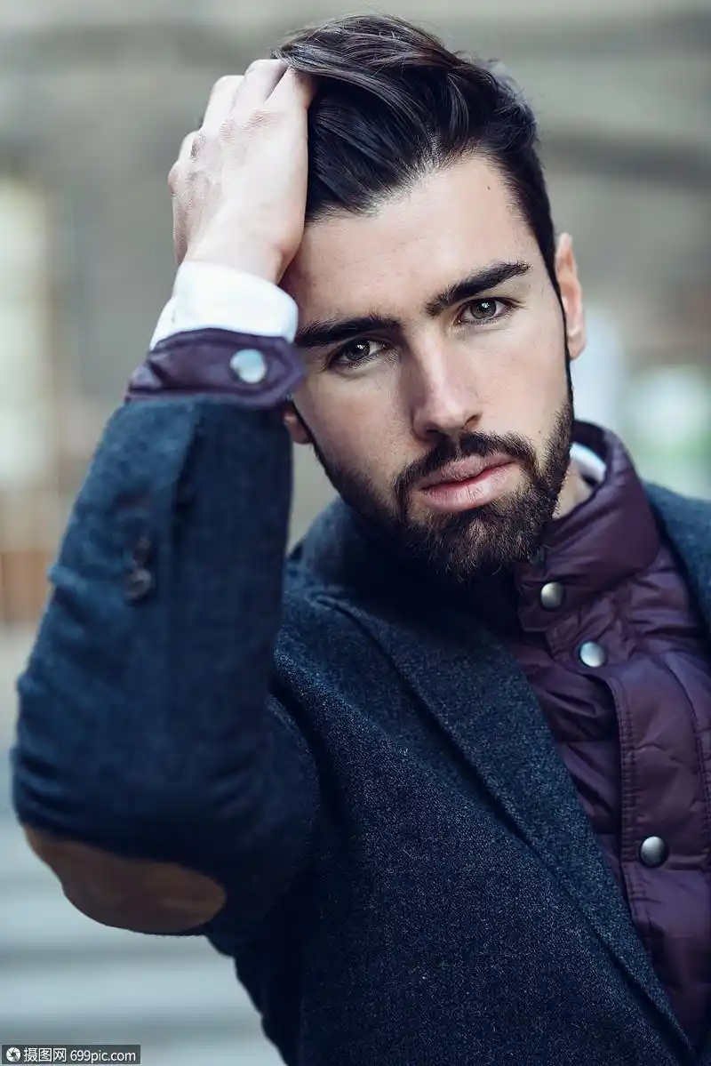 轻的胡须男子时尚模特城市背景下穿着英国优雅的西装留着胡子现代发型