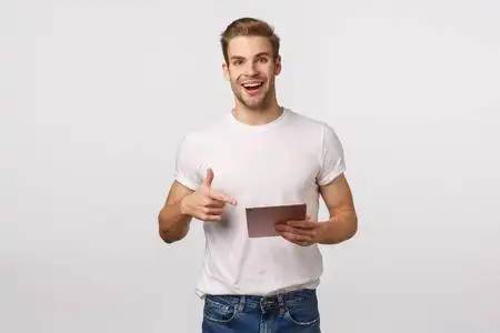 优秀新人笑容可掬的金发白种男同事,穿着t恤衫,牛仔裤,手持数码平板