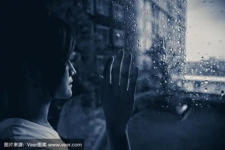 愁眉苦脸的女人望着窗外雨点落下阴暗的心情暗淡的灯光