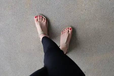 夹脚拖鞋女性脚穿着拖鞋或拖鞋户外红色指甲照片