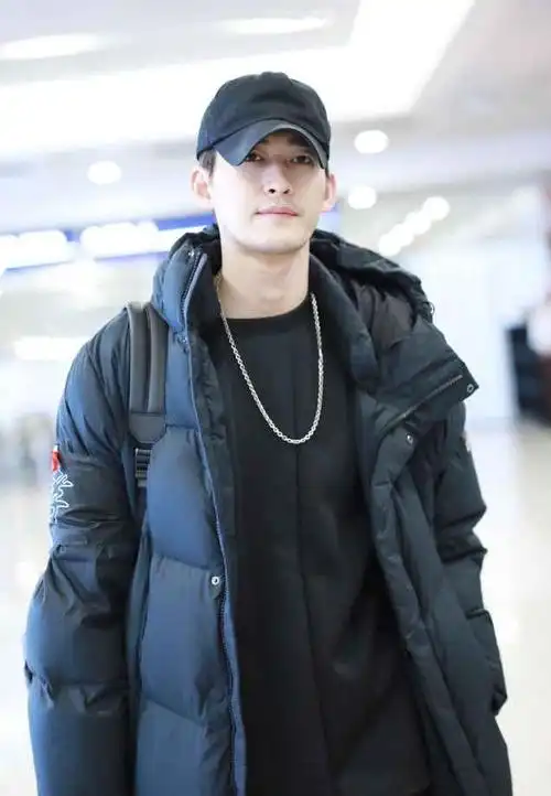 张翰身穿黑色长款羽绒服内搭黑色卫衣现身机场颜值在线精致帅气