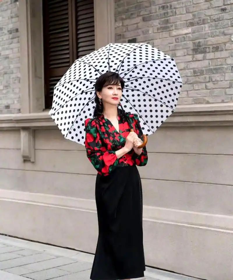 赵雅芝穿着大花朵复古衬衫,搭配黑色长半裙和红色高跟鞋,显得优雅而富