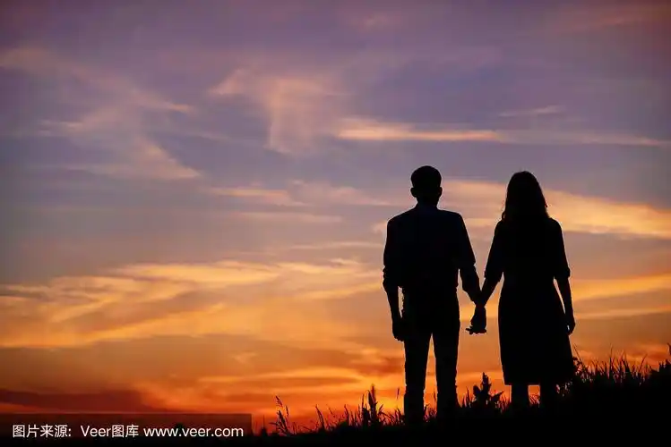 年轻的夫妇是牵着手的背景日落剪影
