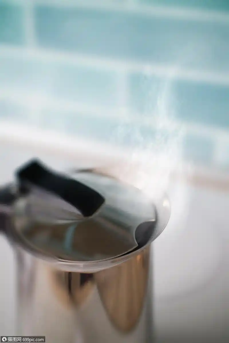 蒸汽厨房蓝色瓷砖的背景上的铁水壶里冒出来茶壶用开水抵厨房的蓝色