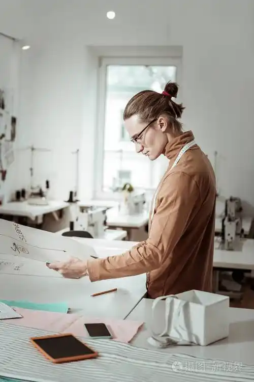 长毛帅气的设计师在一个曲线上工作的棕色服装