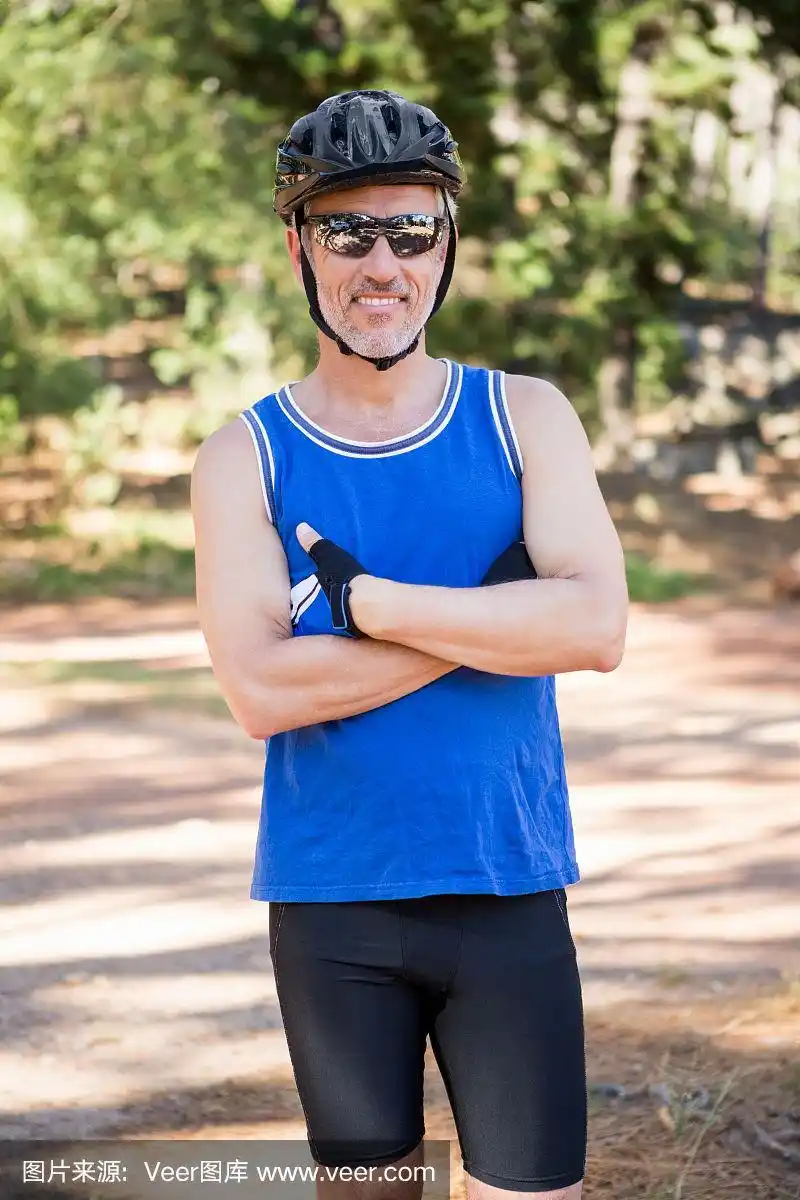 成熟的骑自行车的男人双臂交叉摆姿势