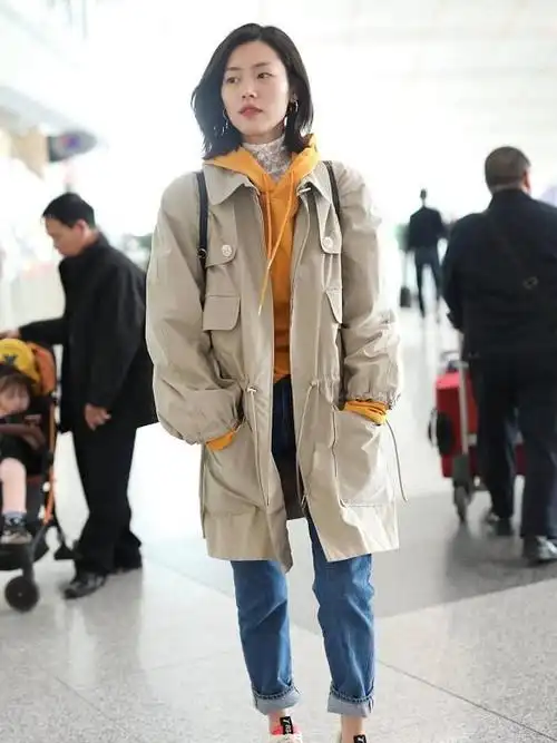 刘雯身穿米色风衣内搭黄色连帽卫衣现身机场打扮休闲时尚如沫春风