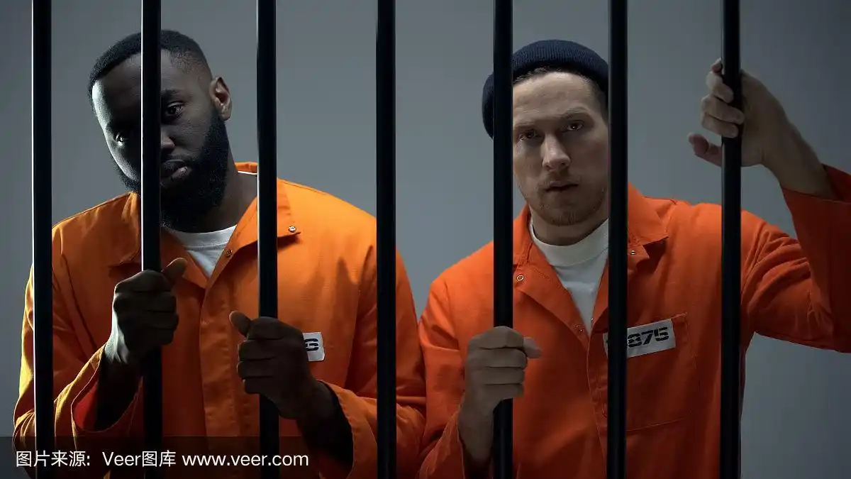 非裔美国人和白人罪犯拿着监狱的铁栏杆看着摄像机