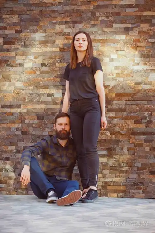 时尚的女人和英俊的胡须男人正在砖背景上摆姿势.