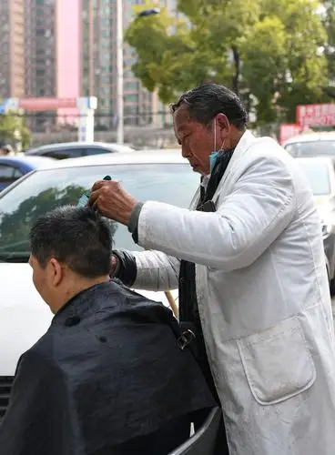 贵阳市云岩区大营坡街头一名路边理发师正在给顾客修剪头发