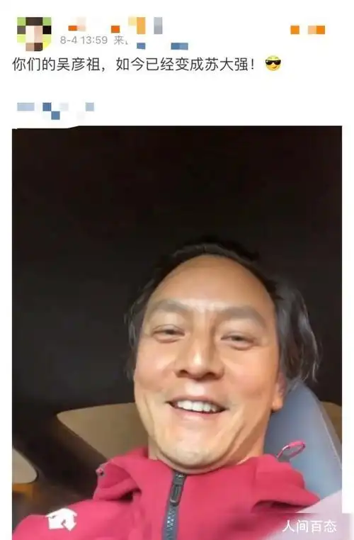 照片中的吴彦祖身着红色连帽开衫,俯视着镜头展露笑容,完全没有任何