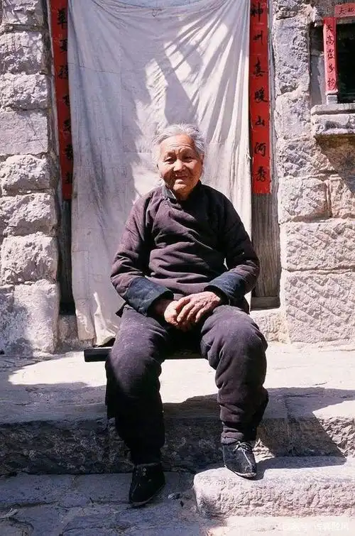 下图 两老人坐在一起手中拿着用酒瓶外包装做的针线盒做起针线来