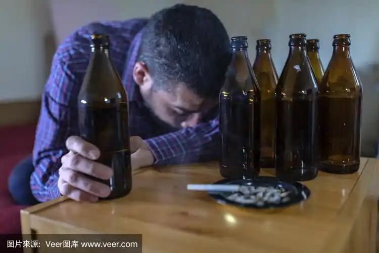 年轻悲伤的醉酒男子喝啤酒和酒精感到浪费,孤独和绝望的痛苦和情绪