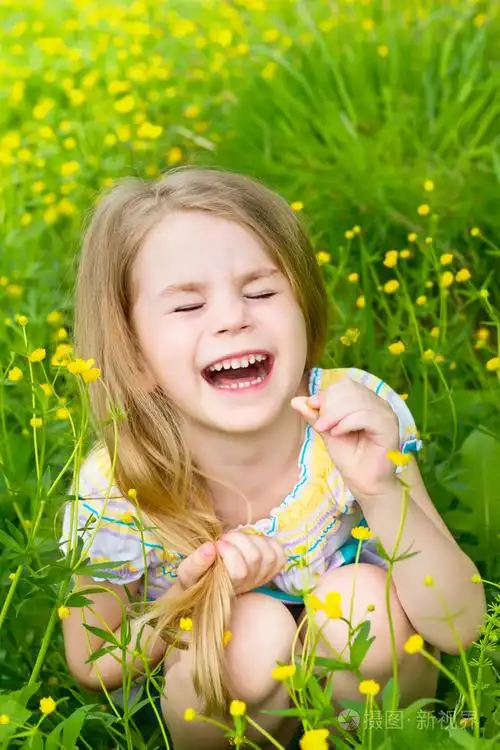 金发碧眼的小女孩笑闭上眼睛坐在草